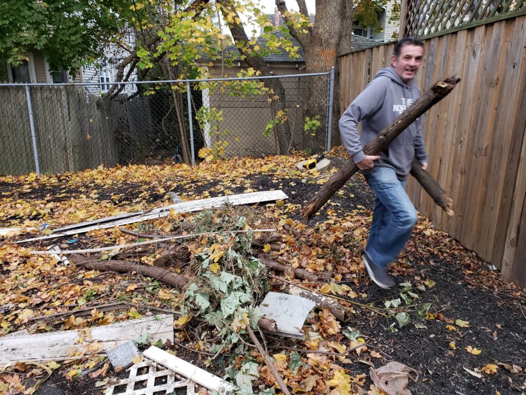 A Green Clover team member removing large tree branches and yard debris from a residential yard in Quincy, MA.