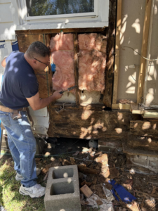 A handyman repairing an exterior wall with exposed insulation at a home in New Orleans, LA, by Richard Earls Construction.