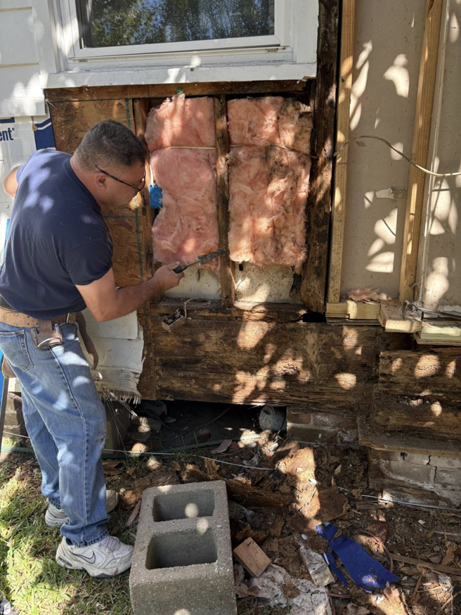 A handyman repairing an exterior wall with exposed insulation at a home in New Orleans, LA, by Richard Earls Construction.