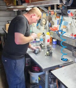 A man repairing small engine parts at a workbench, demonstrating detailed repair services by Tim's Maintenance & Repair in Las Vegas, NV