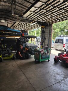 A man repairing a utility vehicle inside a garage, surrounded by other equipment, for Tim's Maintenance & Repair in Las Vegas, NV