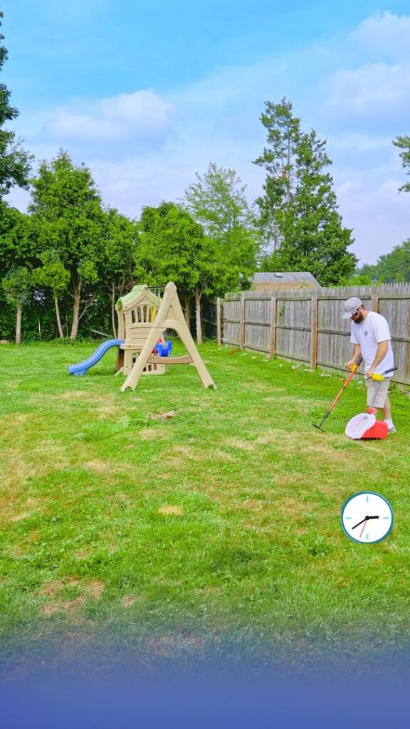 A man scooping dog poop in a residential backyard for Poofect Lawns in Syracuse, NY