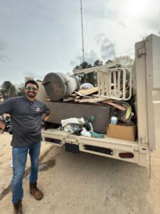 A Dumpzilla team member standing next to a dump trailer filled with various junk and debris in Raleigh, NC.