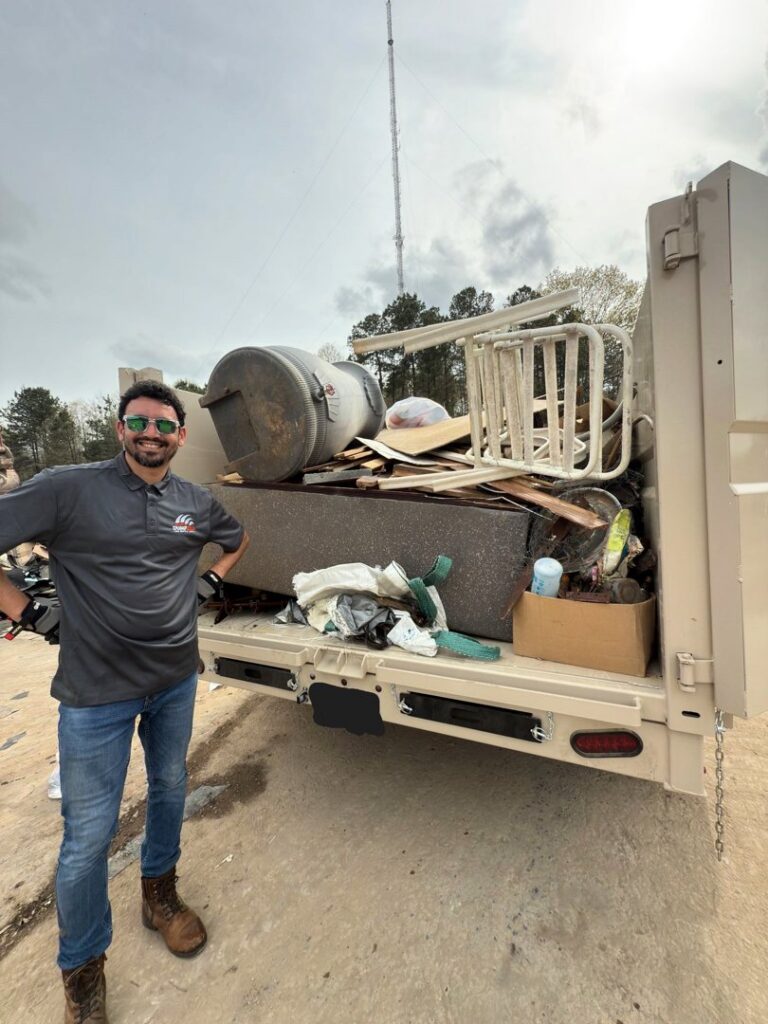 A Dumpzilla team member standing next to a dump trailer filled with various junk and debris in Raleigh, NC.