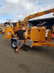 A Starfarm Tree Service Hawaii team member standing proudly next to a large wood chipper in Kapolei, HI.