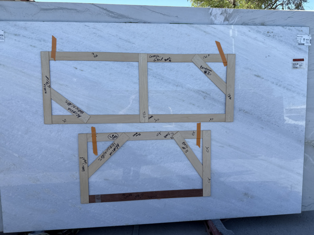 A large marble slab with wooden templates for custom countertop cuts, prepared by Arcadia Building Company in Mesa, AZ.