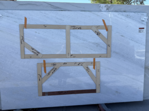A large marble slab with wooden templates for custom countertop cuts, prepared by Arcadia Building Company in Mesa, AZ.