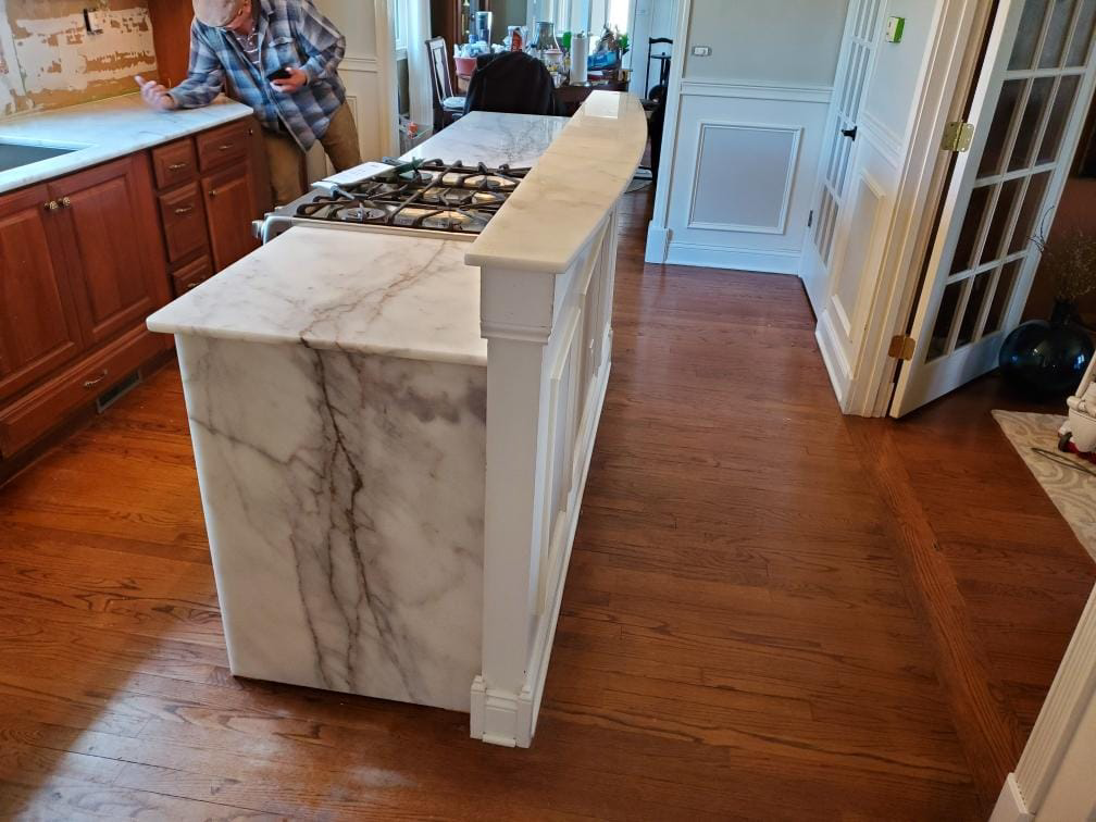Elegant marble kitchen island installation with a gas range by Centennial Granite, a handyman service in New Haven, CT.