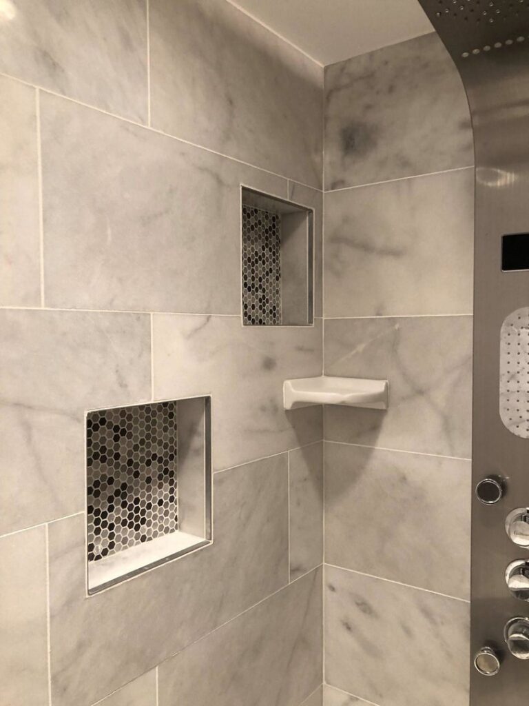Close-up of a shower with marble-look tiles and built-in storage niches completed by FEARS Construction in Nashville, TN.