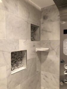 Close-up of a shower with marble-look tiles and built-in storage niches completed by FEARS Construction in Nashville, TN.