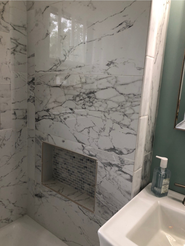 Shower wall with large marble-look tiles and mosaic niche installed by B&W Designer Tile in Tulsa, OK