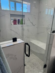 Marble-look tile shower installation with built-in niche by Jocia Construction Services in Gilbert, AZ.