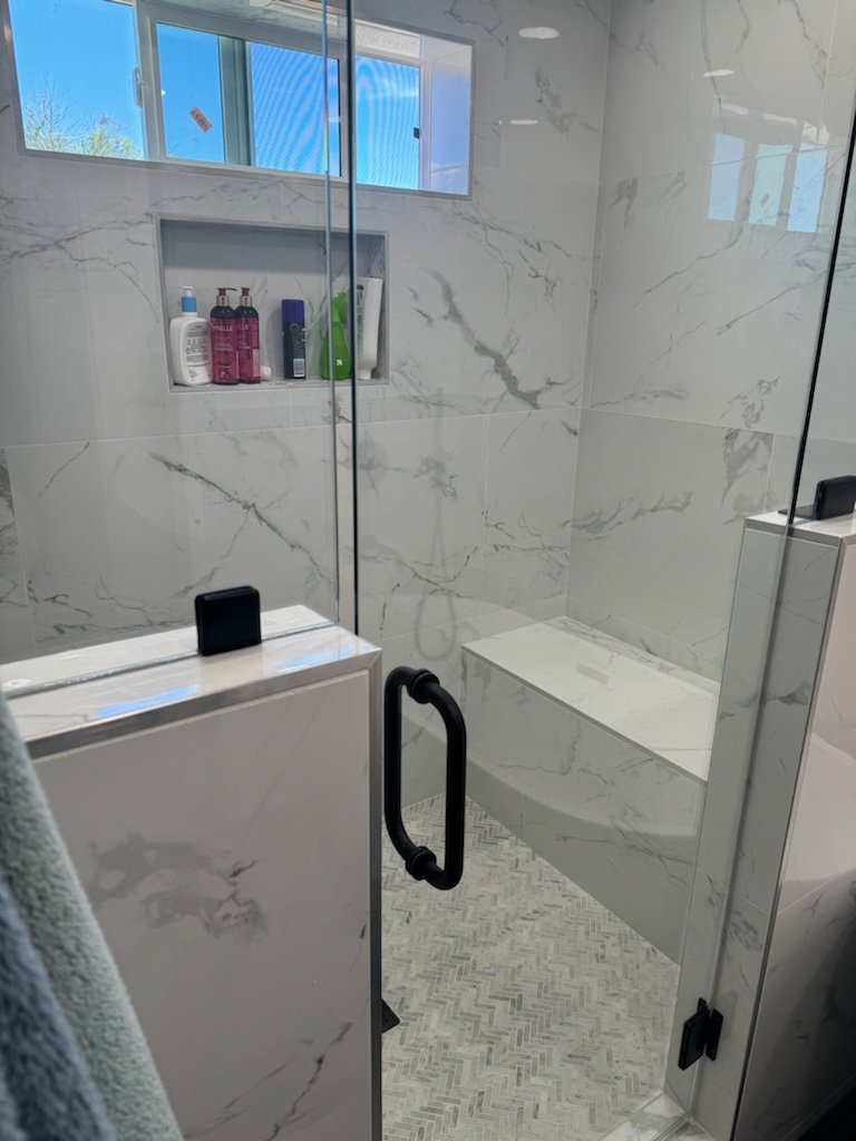 Marble-look tile shower installation with built-in niche by Jocia Construction Services in Gilbert, AZ.