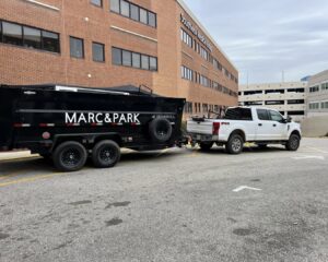 Marc & Park Junk Removal, LLC truck and branded dump trailer parked in Birmingham, AL, ready for service.
