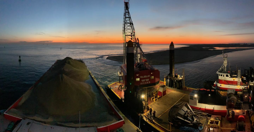 A marine dredging operation with a crane on a barge at sunset by Weeks Marine, Inc. in Cranford, NJ