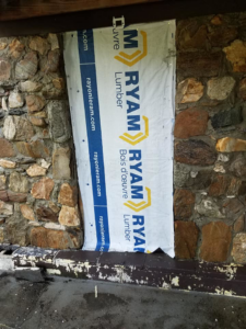 A masonry wall with a section covered by a waterproofing wrap during a project by Stone cutter masonry restoration & waterproofing in Georgetown, KY.