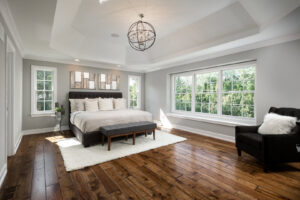 A spacious master bedroom featuring a tray ceiling and hardwood floors, designed by Autumn Homes in Naperville, IL.