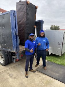 Two 1-800-GOT-JUNK? crew members with a large mattress loaded onto their truck in Bronx, NY