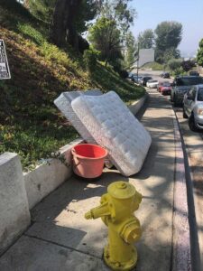 Mattresses and a red bucket left on a sidewalk, ready for general junk removal by BumbleBee Junk in Sun Valley, CA
