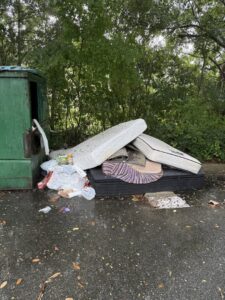 Mattresses, a box spring, and household trash piled next to a dumpster, awaiting junk removal by Reliable Pro in Tallahassee, FL.