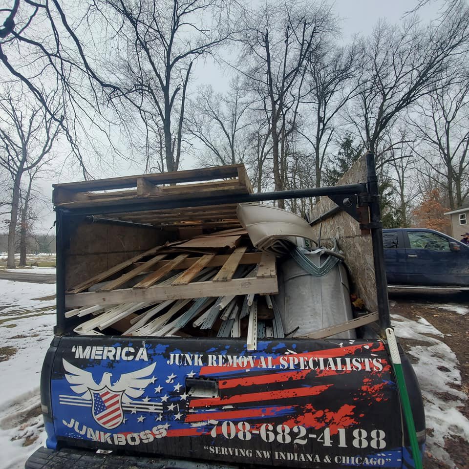 The back of a Merica JunkBoss LLC truck loaded with wooden pallets and construction debris in Gary, IN.