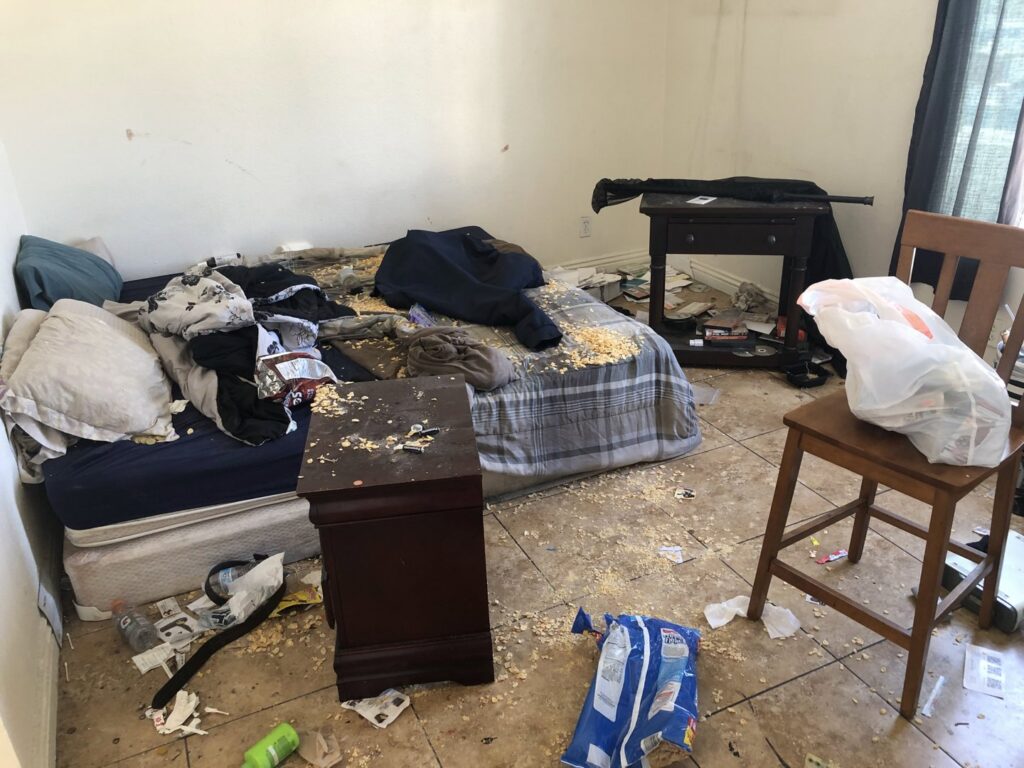 A very messy bedroom with clothes, debris, and trash on the floor and bed, requiring a cleanout service from MLG Strong Hauling & Junk Removal LLC in Henderson, NV.