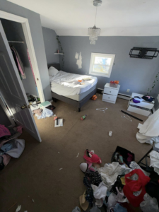 A messy bedroom with clothes and various items scattered, showing a space needing cleanout services from DJ's Junk Removal in Laconia, NH.