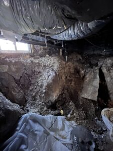 A messy crawlspace filled with dirt and debris, before foundation repair work by Appalachian Foundation Services in Roanoke, VA.