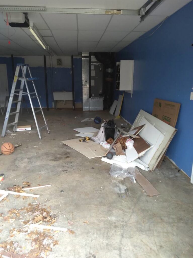 A messy garage or workshop with a ladder and debris, showing a space before cleanout or renovation by JAMS Property Preservation LLC in Dayton, OH.