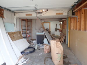 A messy garage filled with construction debris, wood scraps, and various junk items, ready for A1 Junk Removal Of Tucson, AZ.