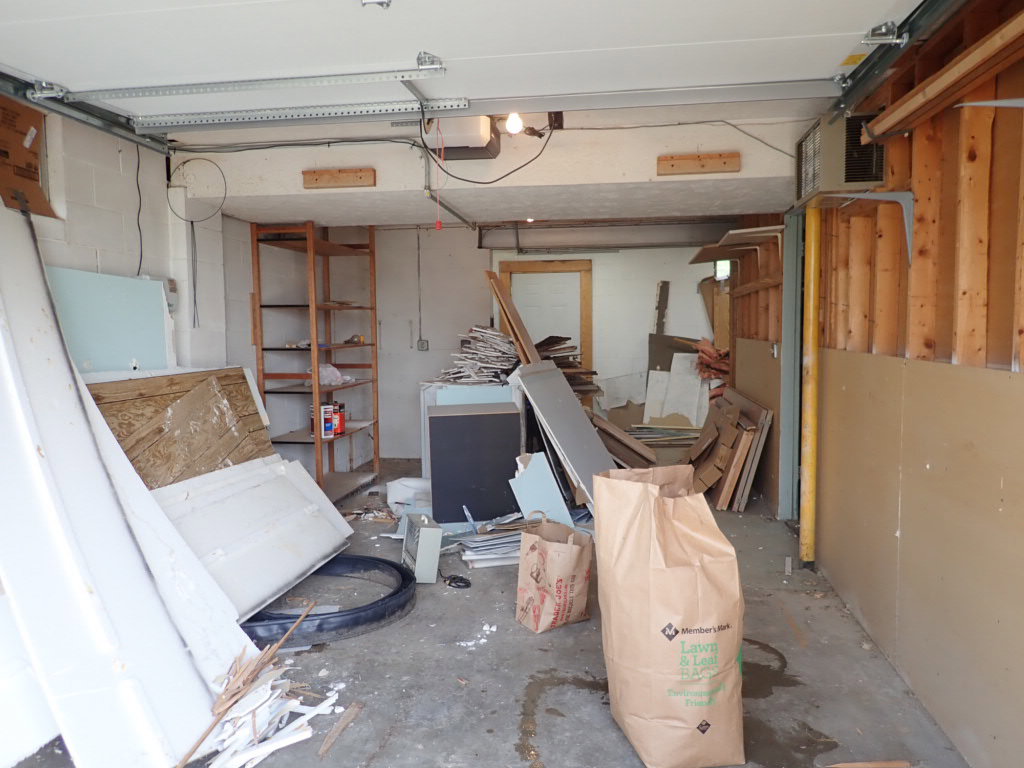 A messy garage filled with construction debris, wood scraps, and various junk items, ready for A1 Junk Removal Of Tucson, AZ.