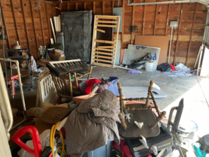 A very messy garage filled with household junk, including furniture and boxes, awaiting cleanup by 575 Junk Removal in Clovis, NM.