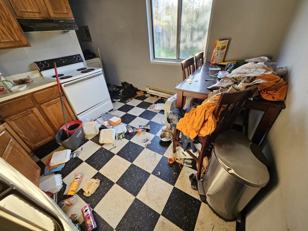 A very messy kitchen with trash and debris on the floor and table, showing a cleanout job by T&G Dumping in Lorain, OH.