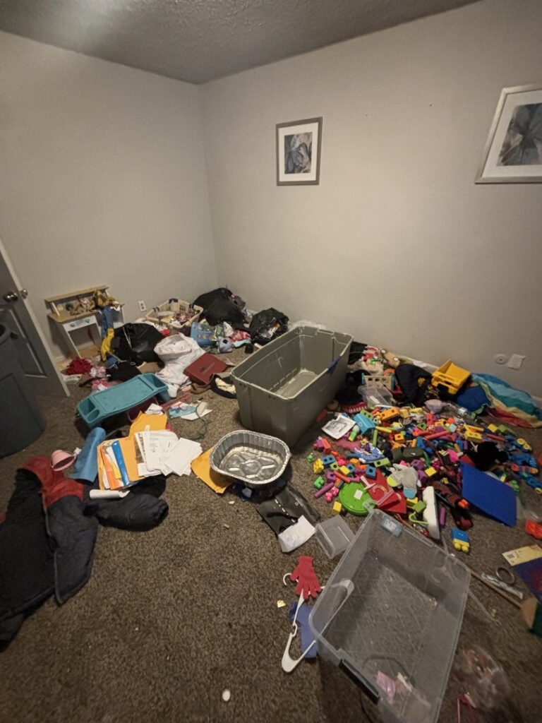 A messy room with toys, clothes, and various debris on the floor, indicating a cleanout job by YEE-HAul Trash Removal in St. George, UT.