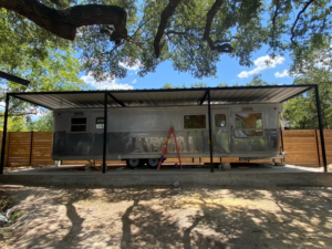 A newly constructed metal carport or awning structure built over a trailer, with a new fence by J&J ultimate roofing llc in Austin, TX