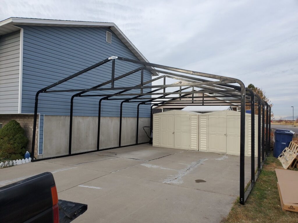Metal carport frame assembly in progress next to a house by Jonny Handyman Services in Roy, UT.