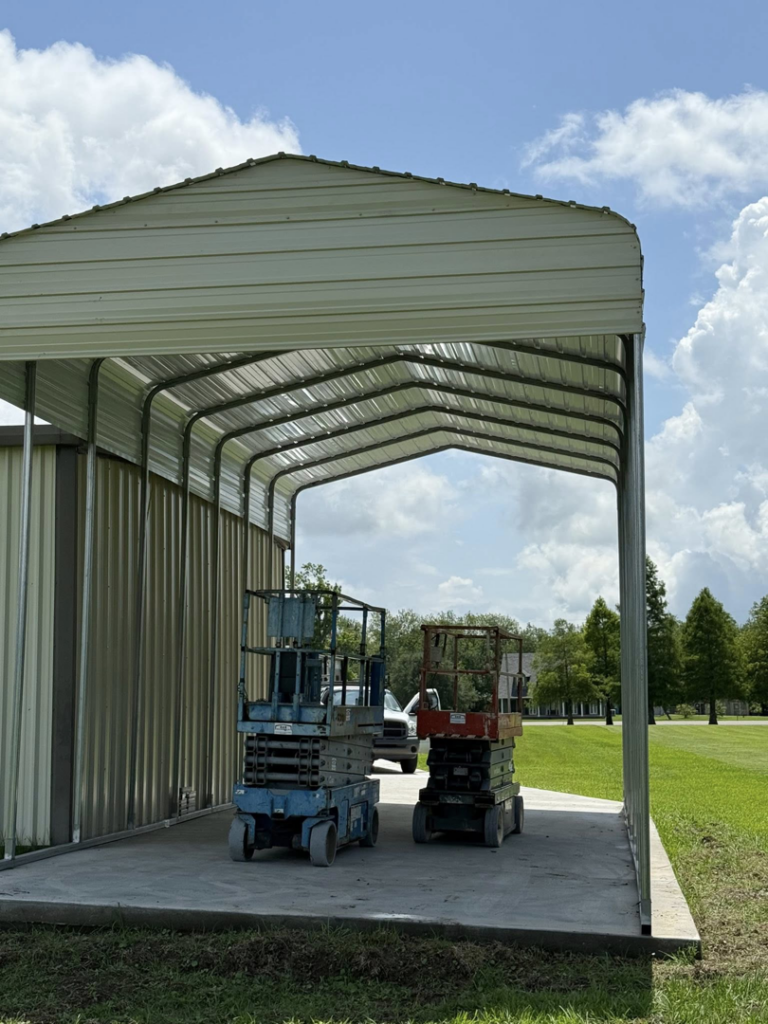 A newly installed metal carport with two scissor lifts parked underneath by B & H Metal Buildings Inc. in Kenner, LA.