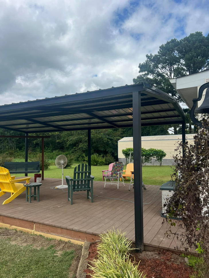 A custom metal-framed patio cover installed over a wooden deck by Boyce Welding, LLC, providing shade in Courtland, VA.