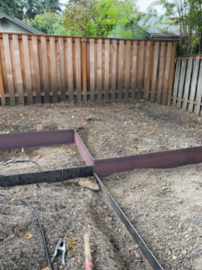Metal borders being installed for a garden bed in a backyard by Loper & Slag metal fabrication design in Portland, OR.