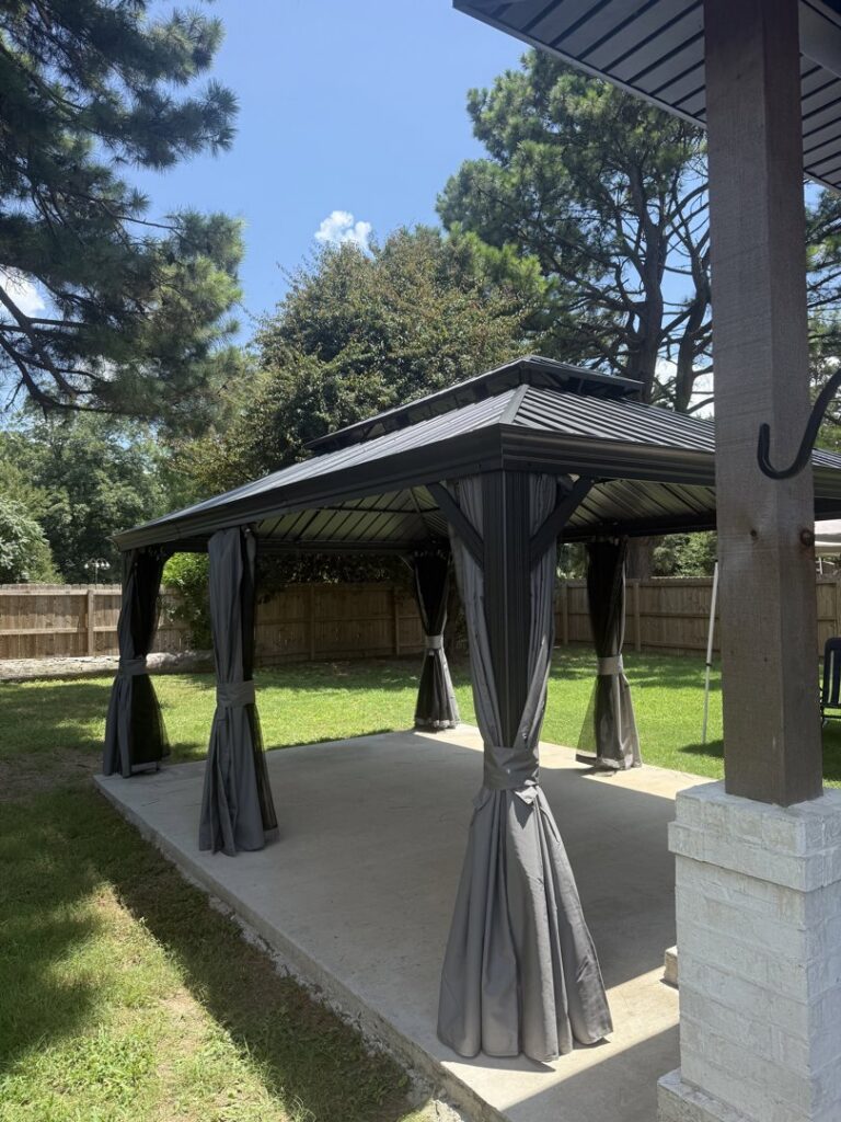 A newly assembled metal gazebo with curtains on a concrete patio by Profix Home Repair in Jonesboro, AR.