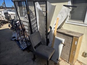 A pile of metal grates, an old chair, and other miscellaneous junk items awaiting removal by Titan Junk Co. in San Diego, CA