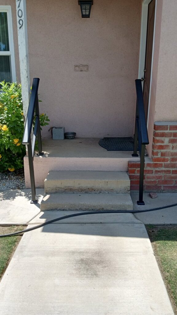 Newly installed black metal handrails on concrete steps by Cal Heights Construction And Handyman Services in Bakersfield, CA
