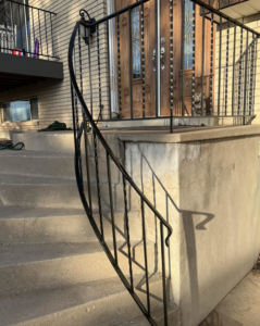 A newly installed or painted black metal railing on concrete steps by Titan Handyman Services in Lewes, DE