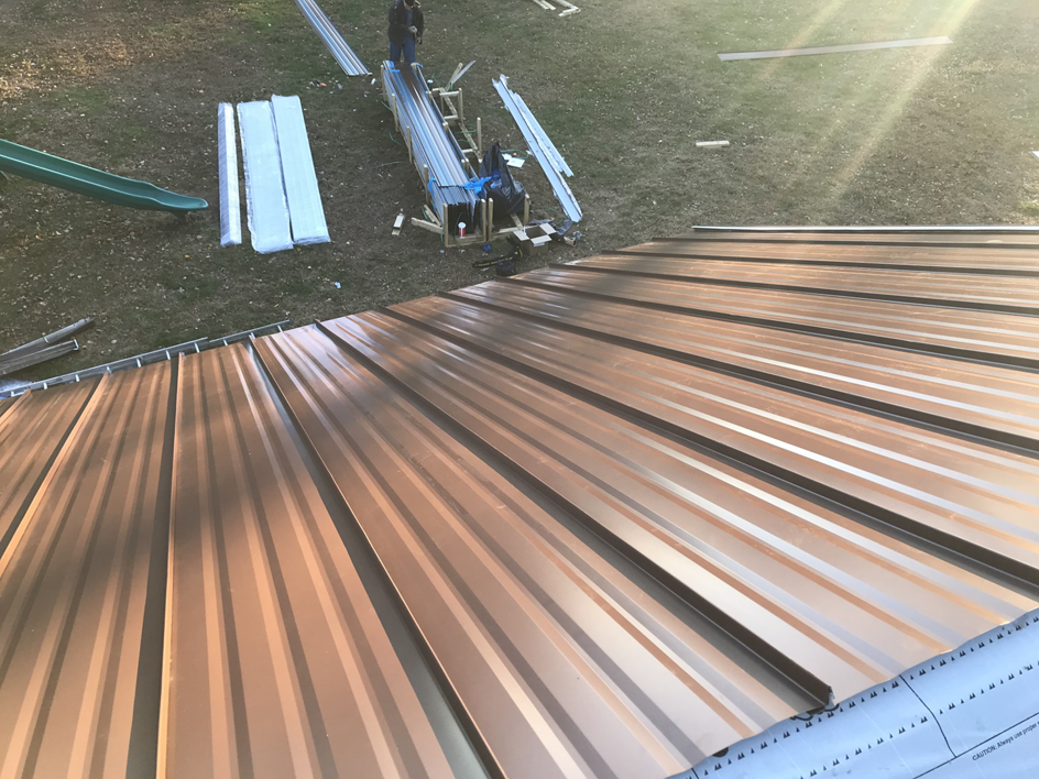 Workers installing a new metal roof on a residential building by Skyline Construction, LLC in Ocean City, MD