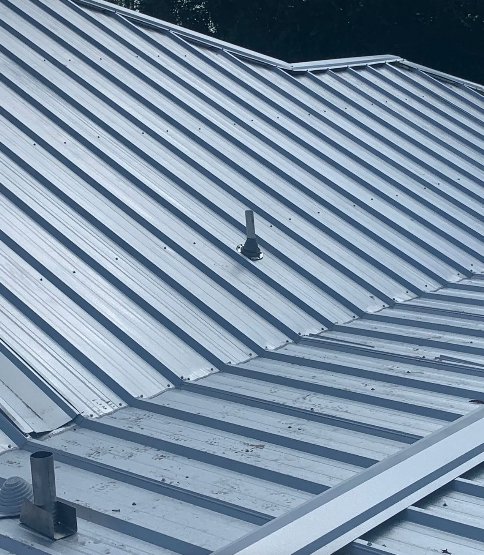 Close-up view of a metal roof with a vent pipe, showcasing quality roofing work by Total Improvements LLC in San Antonio, TX