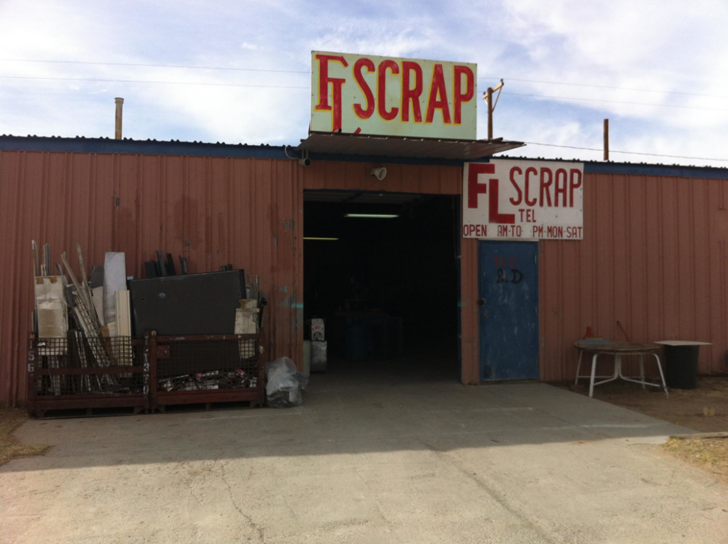 Various metal scrap and junk items piled outside the FL Scrap business entrance in El Paso, TX, ready for general junk removal.