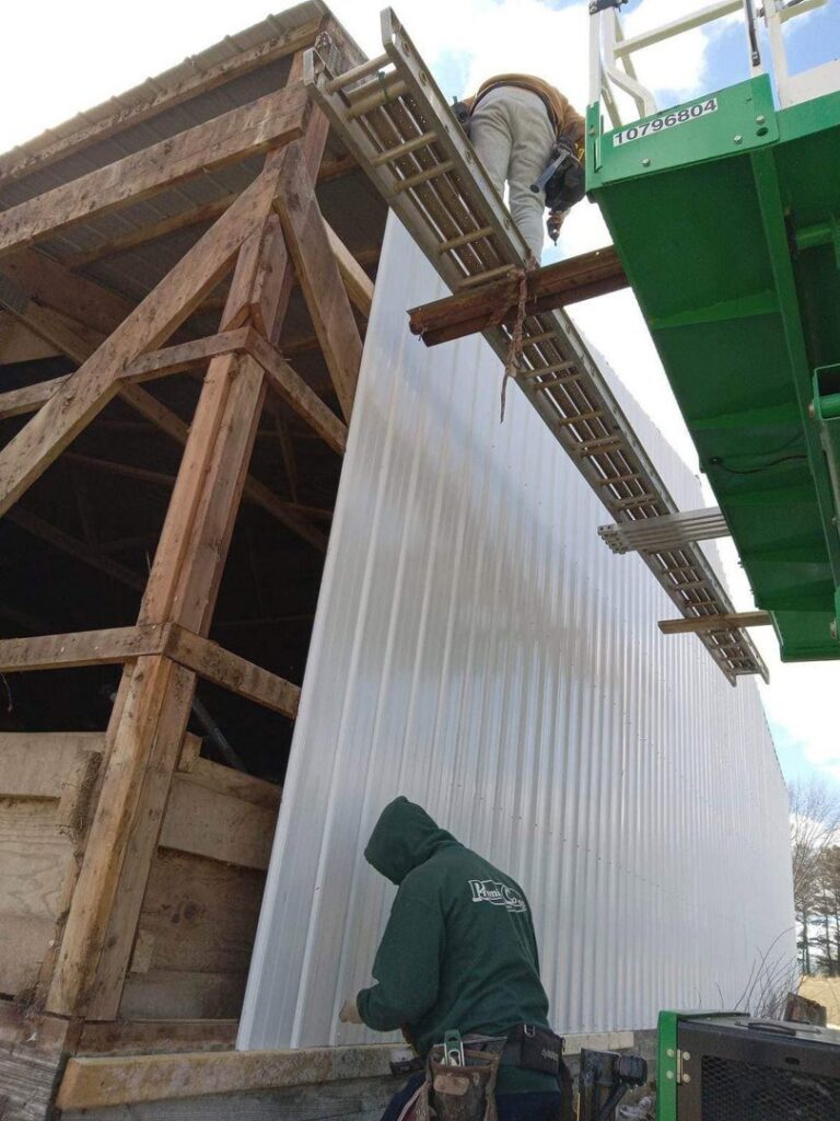 Workers installing metal siding on a barn structure by S-Squared Construction in Madison, WI.