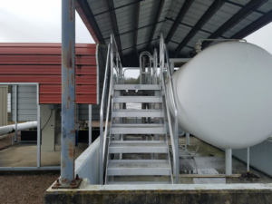 Industrial metal staircase and platform installed next to a large tank by Northwest Access Products LLC in Castle Rock, WA.