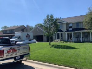 A Metro Insulation truck and equipment parked outside a residential house for an insulation job in Rockford, IL.