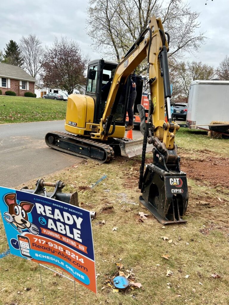 A mini-excavator on a residential street, ready for a construction project by Ready & Able in Etters, PA.